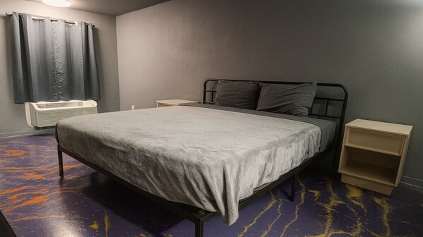 Un dormitorio con cama, mesita de noche, calefactor y cortina.