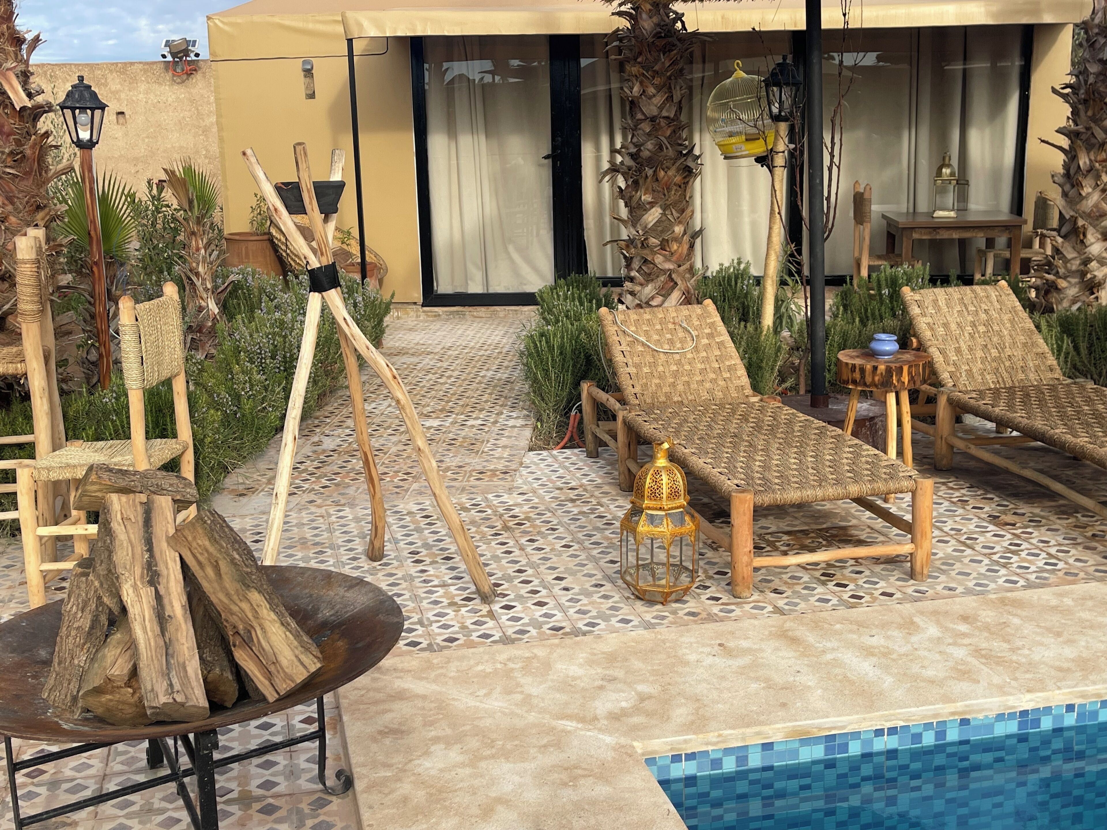 A poolside area with lounge chairs, a wooden table, and a small pool.