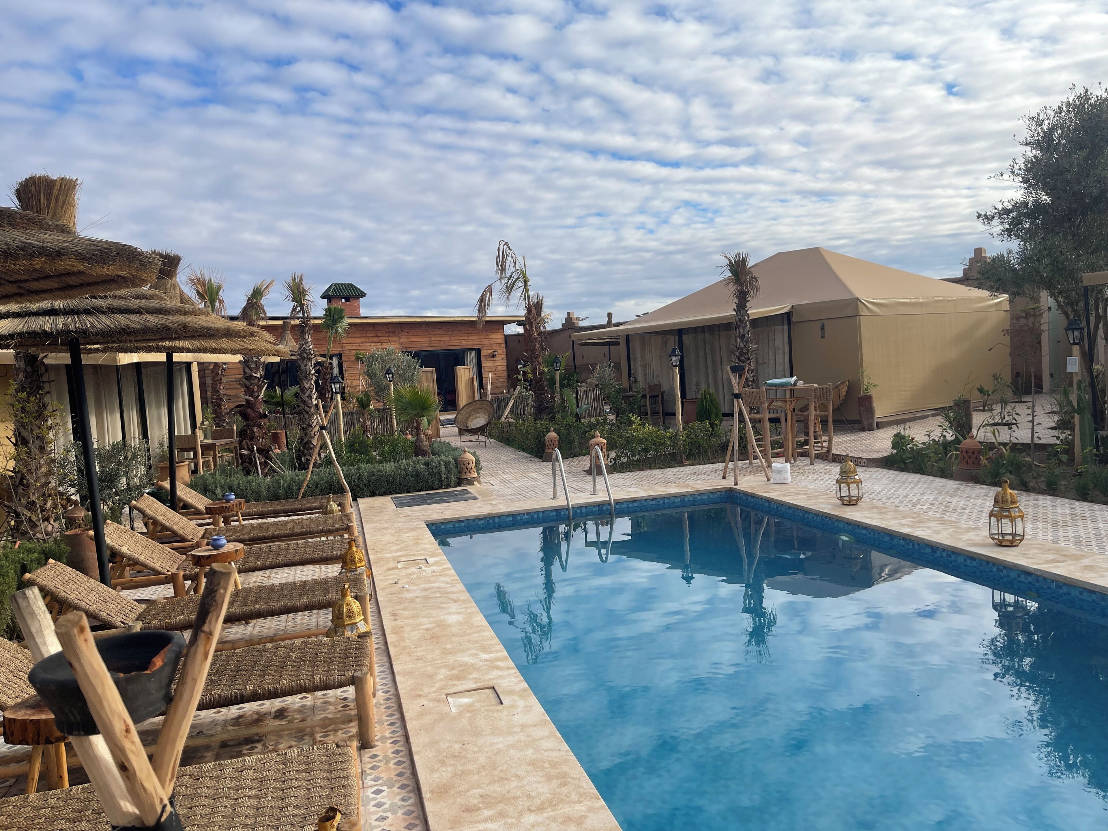 Un área de piscina con sillones de descanso y una carpa.