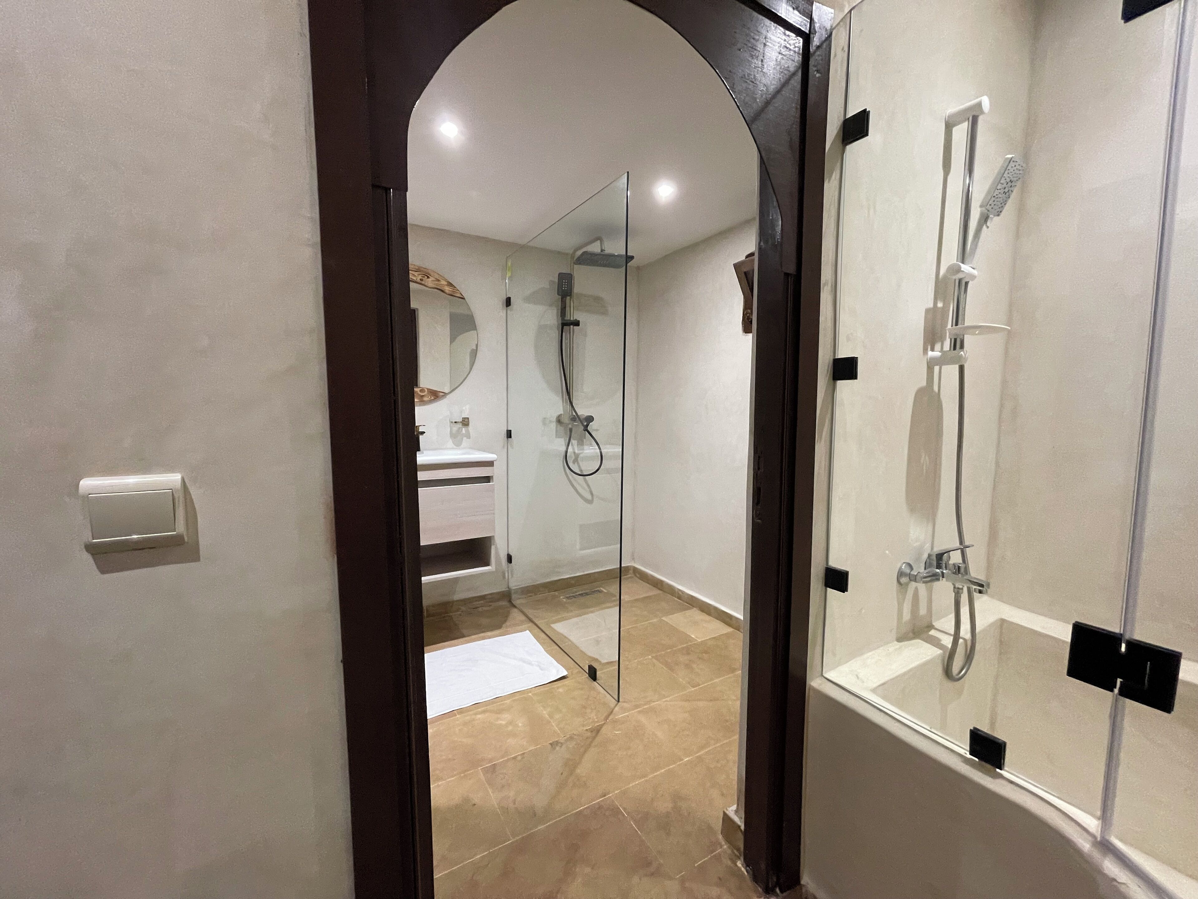 Un baño moderno con ducha envuelta en vidrio, un lavabo blanco y un espejo.