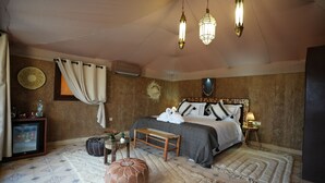A bedroom with a bed, bedside table, lamp, and a fan.