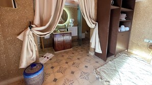 A room with a bed, a wooden cabinet, a sink, and a mirror.