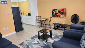 A living room with a sofa, a coffee table, and a dining area with a table and chairs. - Stunning Ocean, City & Pool View 2 Bedroom Apt. 2 minutes from Roseau (Roseau)