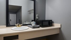 A bathroom with a sink, mirror, towel rack, and a microwave. - 110 Gated King Bed Hotel Room (Jackson)