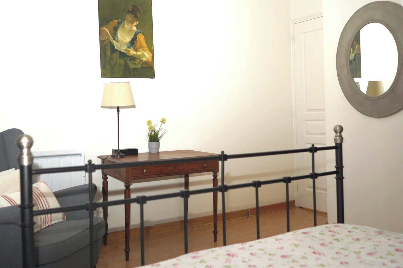 Une chambre à coucher avec un lit, un bureau, une chaise, une lampe et un tableau au mur.