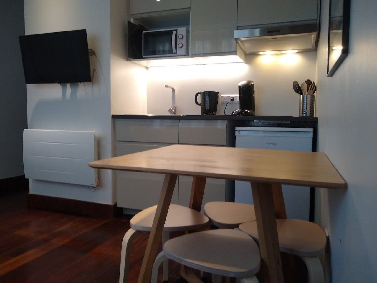 Une cuisine compacte équipée d’un four à micro-ondes, d’une machine à café et d’une petite table à manger avec des chaises.