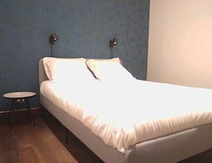 A single bed with white bedding in a room with blue walls and a small round table. - Two Bedroom apartment in historical  center (Bordeaux)