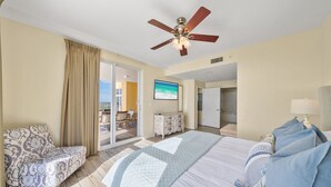 Une chambre d’hôtel avec un lit, une chaise, une télévision et un balcon offrant une vue.