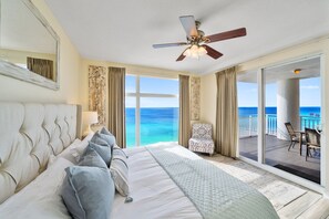 Un dormitorio amplio con una cama grande, un ventilador de techo y vistas al océano a través de un ventanal corredero.