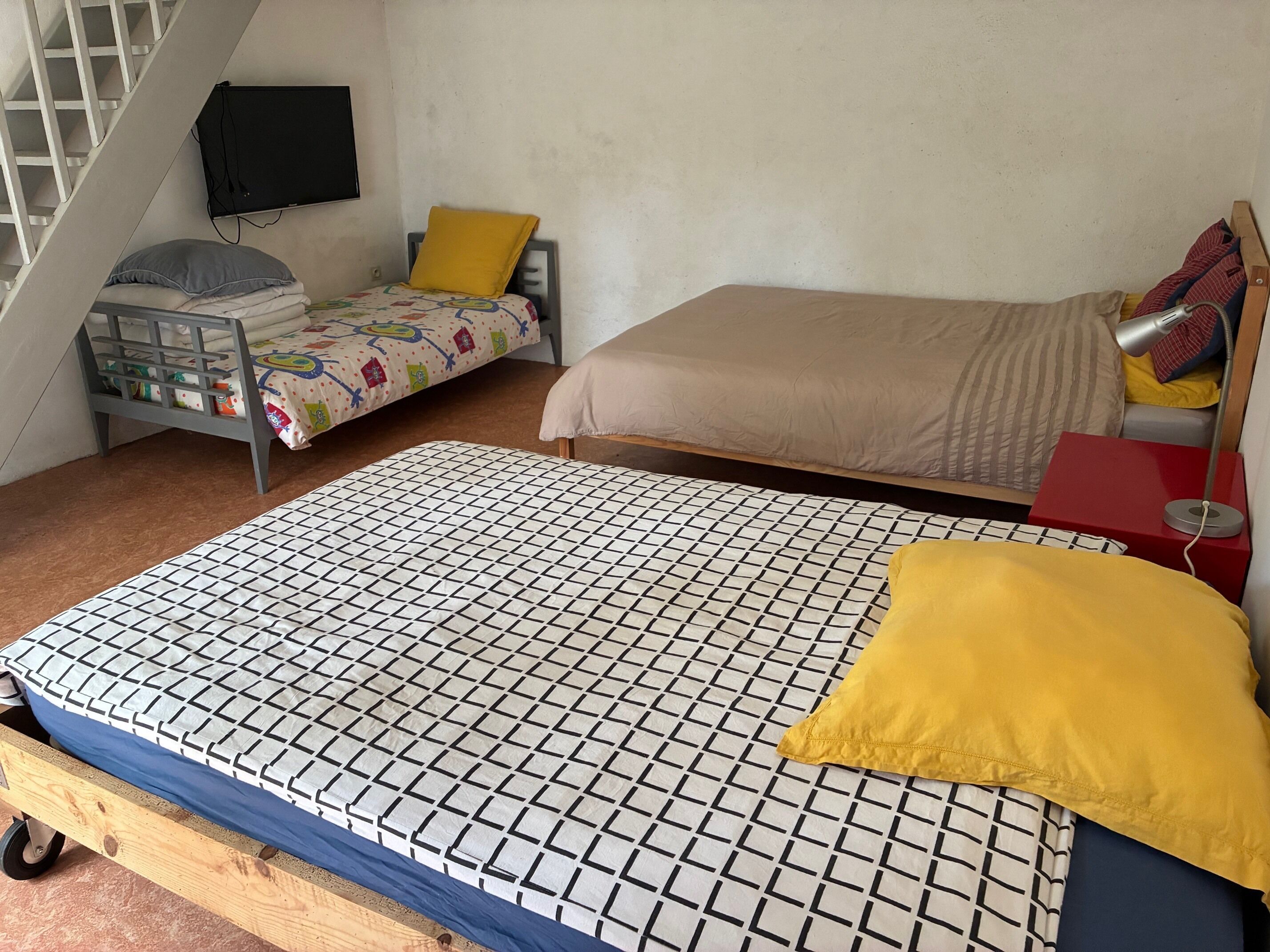 Un dormitorio con una cama grande, otra más pequeña, un escritorio y una silla.