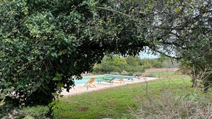 A pool area with lounge chairs and a stone wall. - Country house in the Lot (Concots)