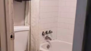 A bathroom with a toilet, a bathtub, and a shower area. - 114 Gated King Bed Hotel Room (Jackson)