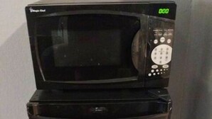 A black refrigerator with a microwave on top, a digital display, and a small blue sticker. - 114 Gated King Bed Hotel Room (Jackson)