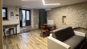 Ein modernes Wohnzimmer mit einer Steinwand, einem Holzesstisch und einer Couch.