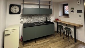 Eine kompakte Küche mit modernem Design, ausgestattet mit einem eingebauten Herd, einem kleinen Kühlschrank und einer Holz Arbeitsplatte.
