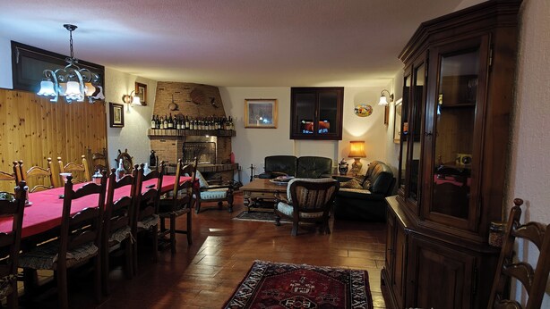 A cozy living room with a fireplace, dining area, and a large wooden cabinet. - Apartment in Villa Jolanda (Romano d'Ezzelino)