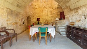 Una habitación con paredes de piedra, una mesa redonda, sillas y un aparador de madera.