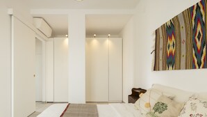 A modern, minimalist bedroom with a large bed, a nightstand, and a wall-mounted artwork. - Cagliari panoramic view by Propertize (Cagliari)