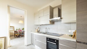 A modern kitchen with a built-in dishwasher, stainless steel sink, and light-colored cabinetry. - Cagliari panoramic view by Propertize (Cagliari)