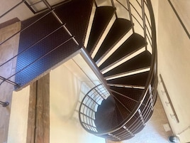 Una escalera en espiral con barandillas de metal y piso texturizado.