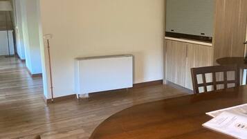 Un salón de conferencias con una mesa redonda de madera, paredes blancas y un radiador.