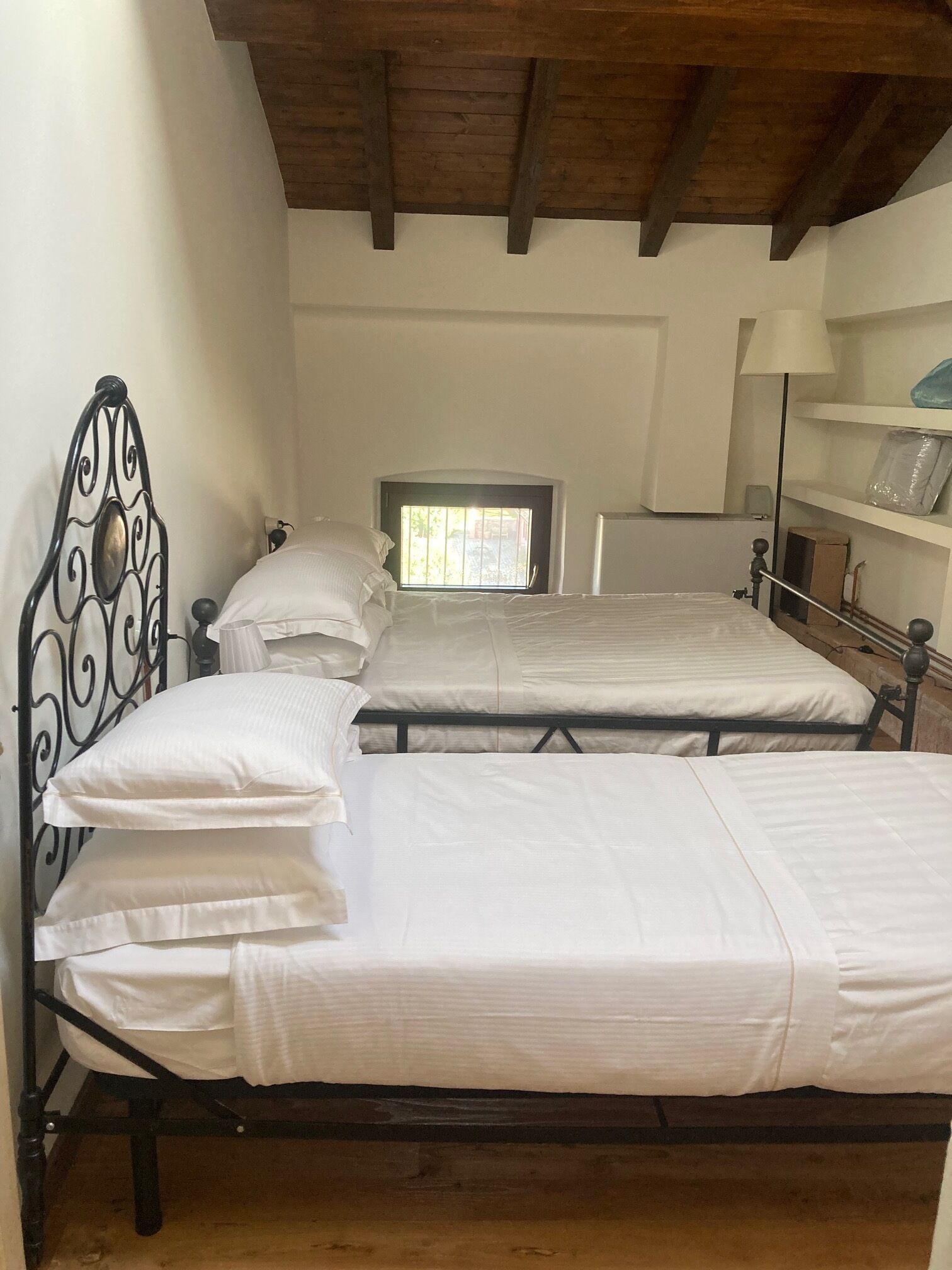 Un dormitorio con dos camas, una ventana y techo de madera.