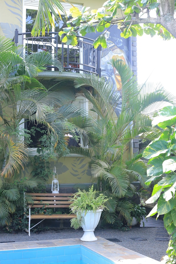 A pool area with a wooden bench and potted plants.
