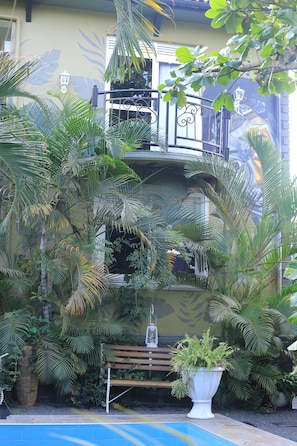 A courtyard with a bench, potted plants, and a pool.