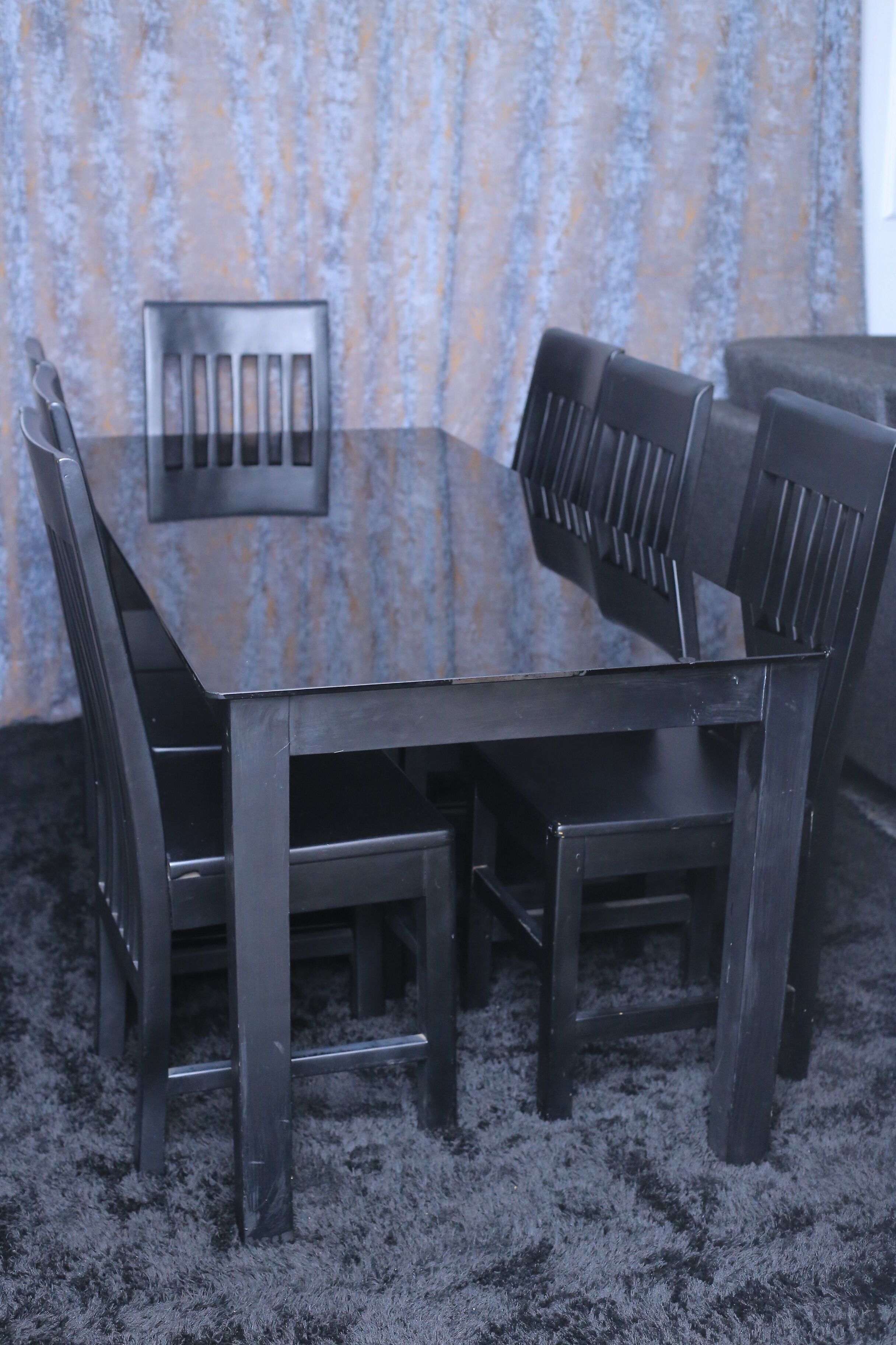 Une table à manger avec des chaises, une bouche d’aération et un mur décoré de motifs.