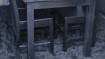 Une table à manger avec des chaises, une bouche d’aération et un mur décoré de motifs.