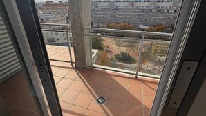 A balcony with a view of a cityscape, a concrete pillar, and a tiled floor. - Apartament H&C (Madrid)