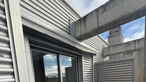 A modern building with a terrace featuring a sliding glass door leading to a bedroom with a bed and a white curtain. - Apartament H&C (Madrid)
