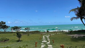 Un sendero que lleva a una piscina con vista al océano y sombrillas de playa.