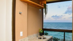 Una cocina con un amplio ventanal con vistas al océano, encimera de granito y una planta colgante.