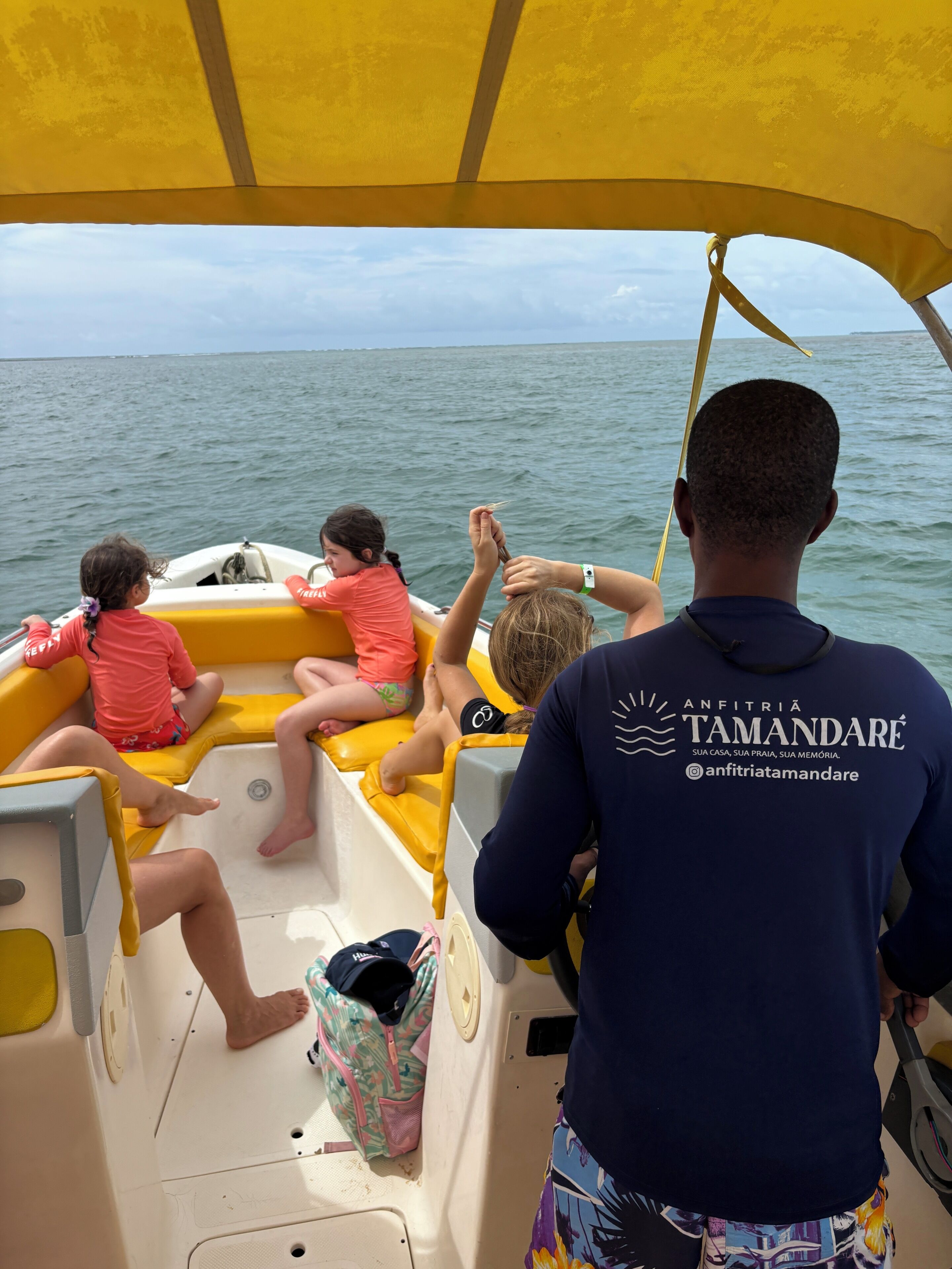 A boat with passengers, a steering wheel, and a person in a blue shirt with a logo.