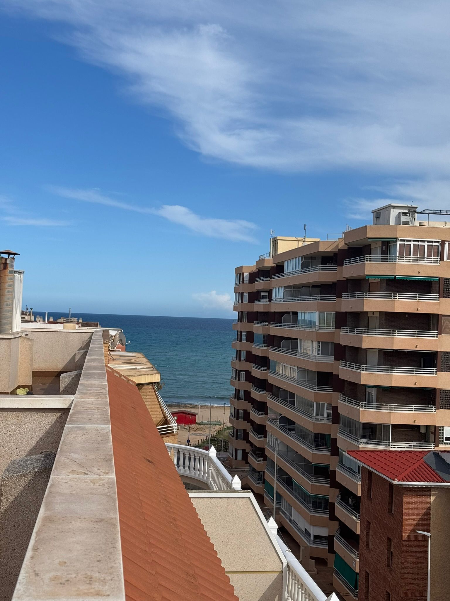 A multi-story building with balconies overlooking a beach.