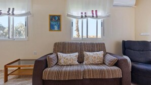 Una sala de estar con un sofá a rayas, un sillón oscuro y una pequeña mesa de madera.
