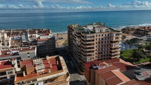 Una zona urbana costera con edificios de varios pisos, una playa y una vista despejada del mar.