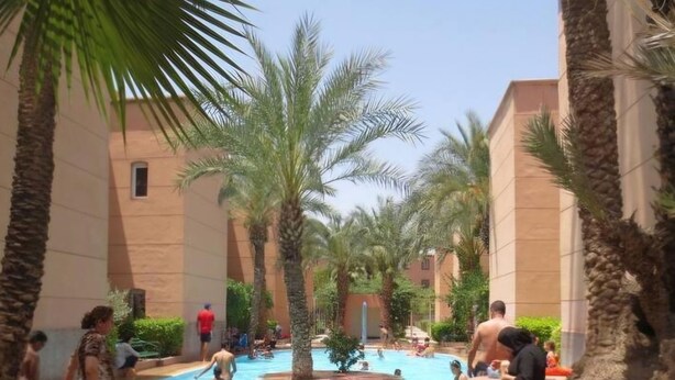 A swimming pool area with palm trees and people swimming. - 3-bedroom Riad in enchanting Marrakech, Wifi and Pool (Marrakech)