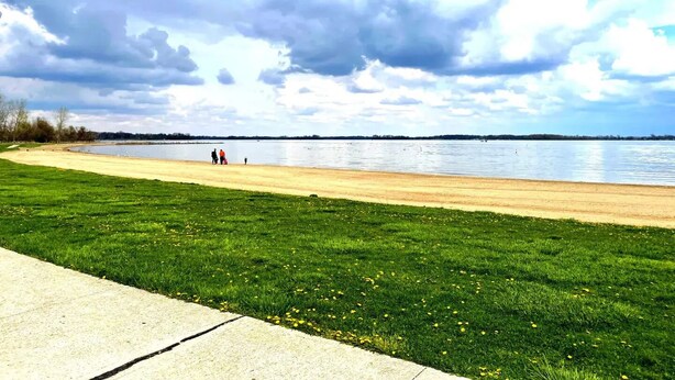 A park with a grassy area, a concrete path, and a body of water in the background. - Lake Life for Two -Walk to Marina + Close to Beach (Lakeview)