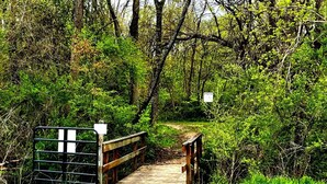 A wooden bridge over a dirt path in a wooded area with signs indicating caution. - Lake Life for Two -Walk to Marina + Close to Beach (Lakeview)