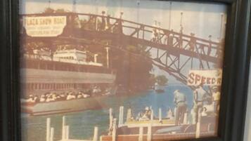 A framed picture of a historic bridge with a boat and people.