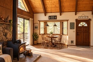 A cozy cabin interior with a fireplace, dining area, and a sign reading 'To the Lake'.