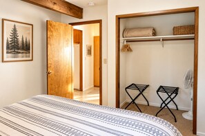 A bedroom with a bed, a wooden door, a closet with shelves, and a fan. - Family Cabin Near Murphys | Lake, Hiking & Stargazing (Arnold)