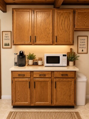 A kitchen with wooden cabinets, a microwave, a coffee maker, and two framed signs on the wall. - Family Cabin Near Murphys | Lake, Hiking & Stargazing (Arnold)