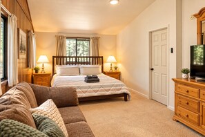 A bedroom with a bed, a sofa, a television, and a door.