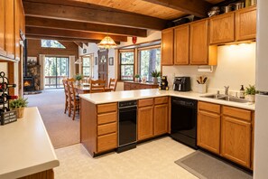 Una cocina con armarios de madera, lavavajillas y cafetera.