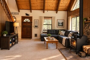 A cozy living room with a fireplace, a sofa, a coffee table, and a television.