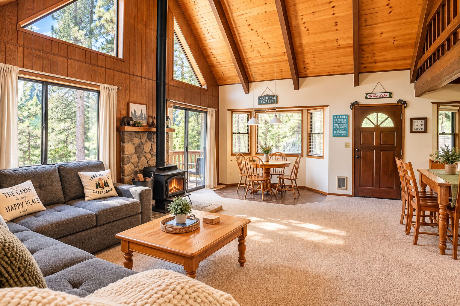 Interior de una cabaña con chimenea, muebles de madera y ventanas amplias.
