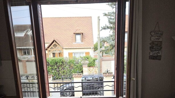 A compact living space with a view of a residential area, a radiator, a small table with a plant, and a sofa. - Studio in Champigny sur marne near Disneyland (Champigny-sur-Marne)
